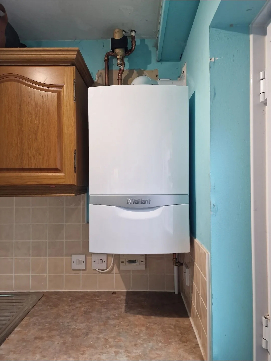 Vaillant combi boiler tucked neatly into a kitchen cupboard with upgraded copper pipework