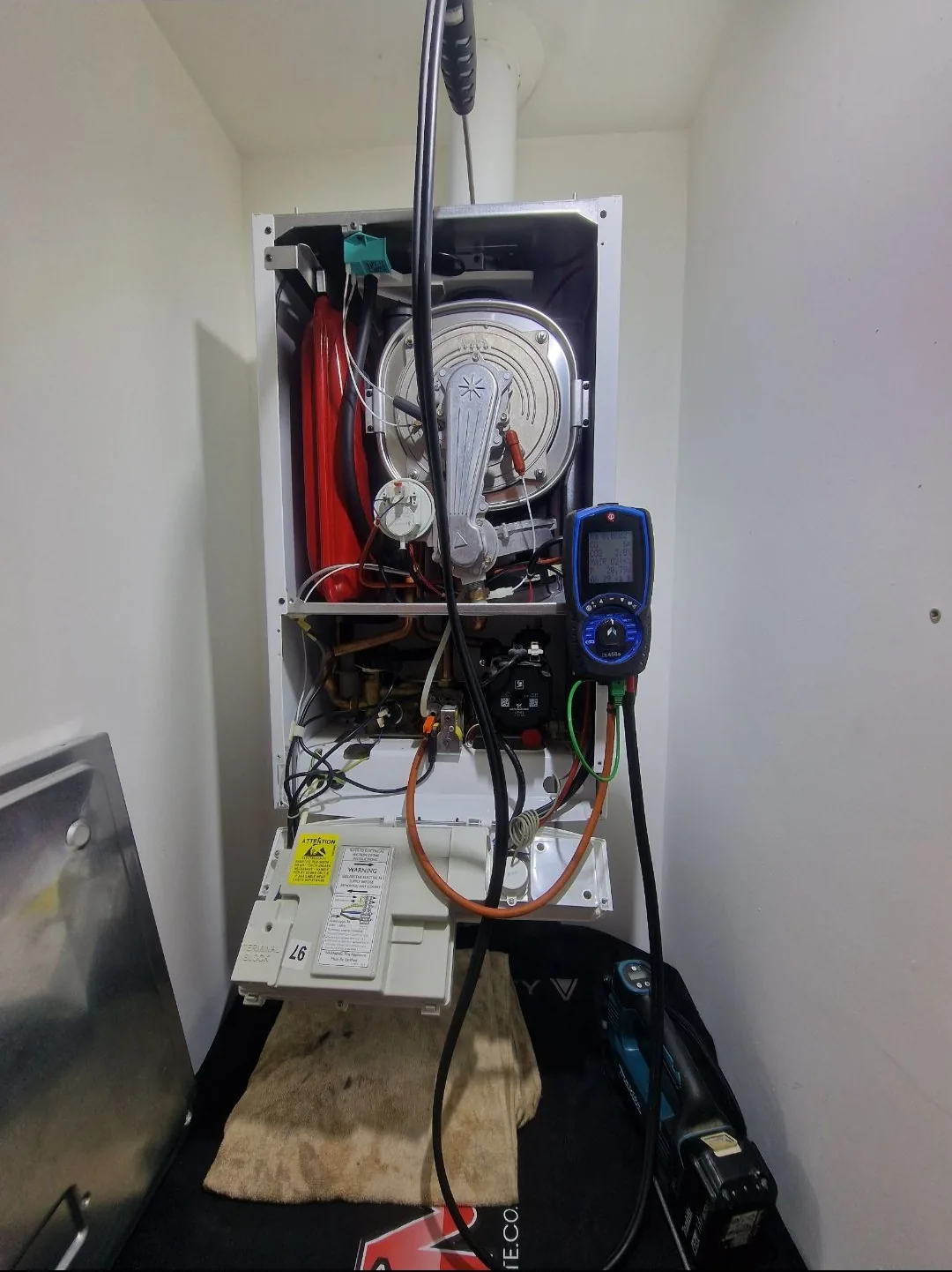 Baxi boiler opened up in a kitchen cupboard for diagnostic testing with parts laid out cleanly